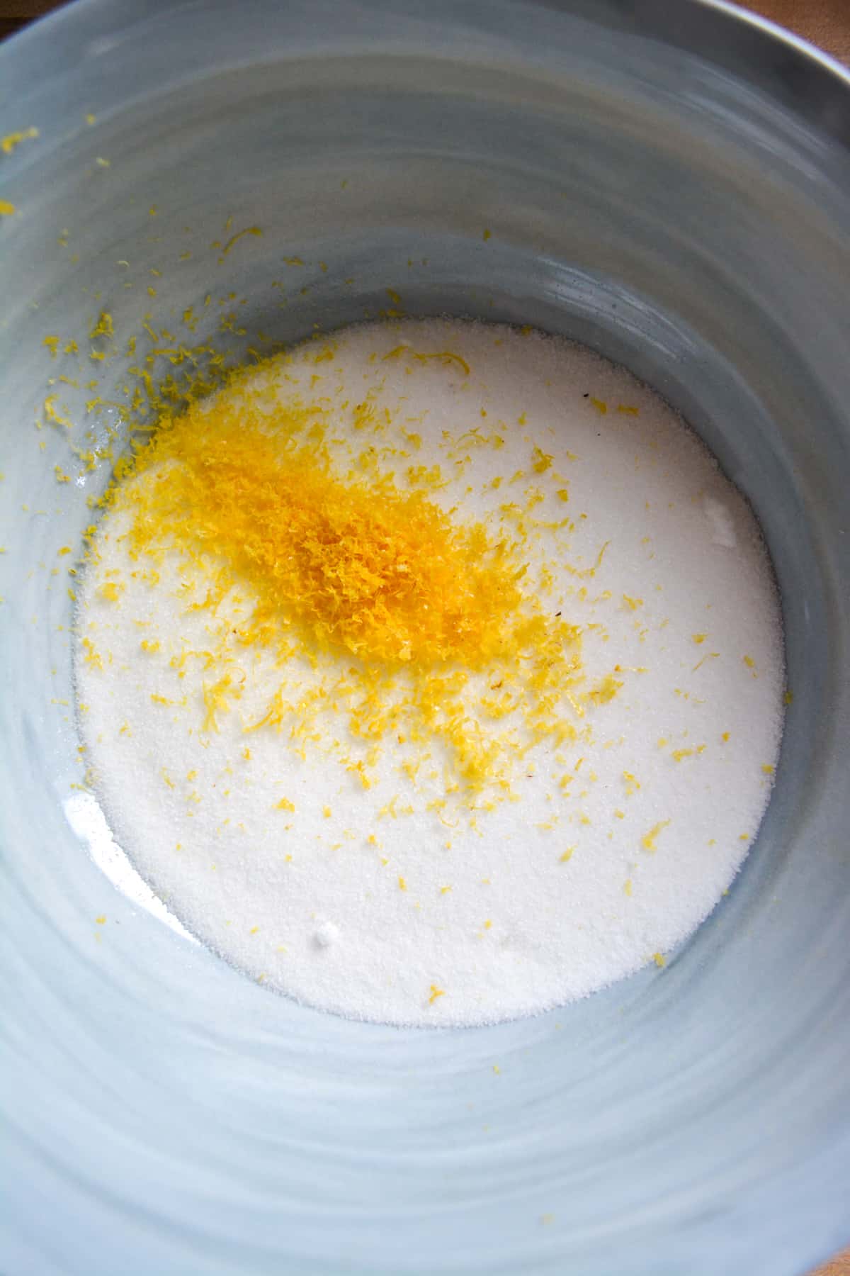 Lemon zest and granulated sugar in a marble mixing bowl.