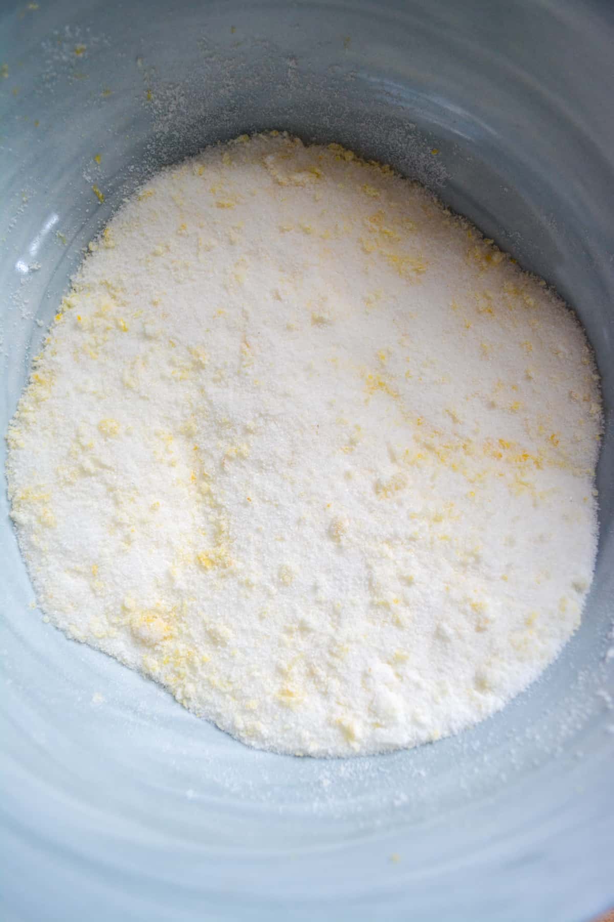 Lemon zest rubbed into the granulated sugar in a mixing bowl.