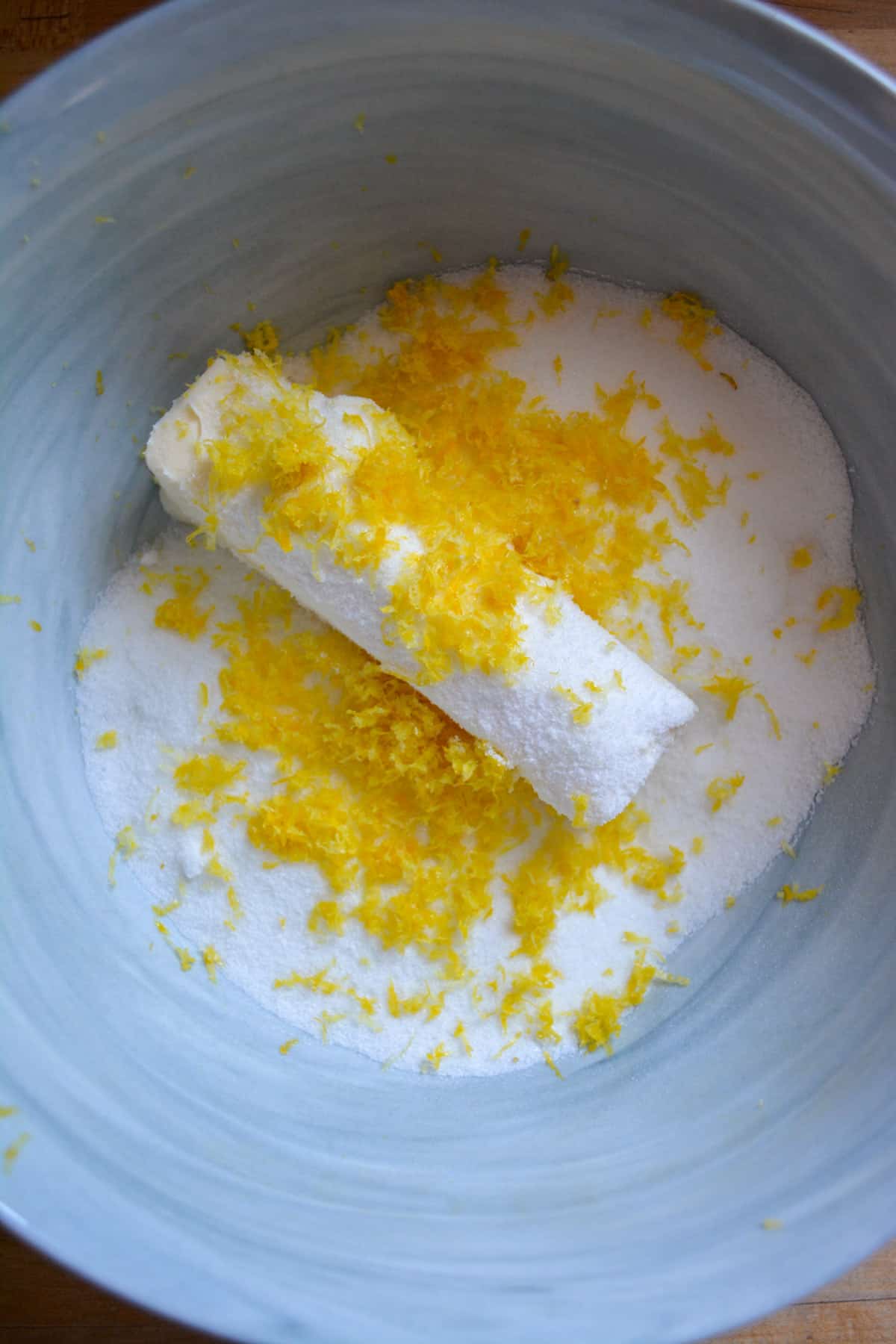 Vegan butter, sugar and lemon zest in a marble mixing bowl.