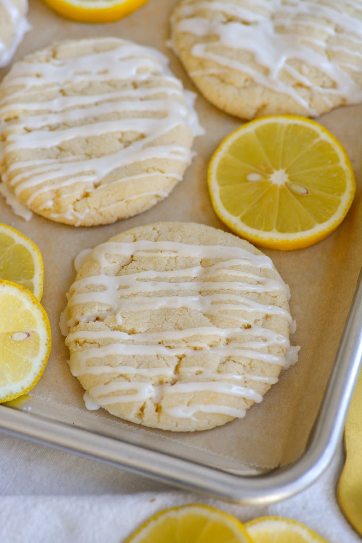 Vegan Lemon Sugar Cookies on a baking sheet with lemon slices in the scene.