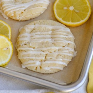 Vegan Lemon Sugar Cookies on a parchment-lined baking sheet with lemon slices.