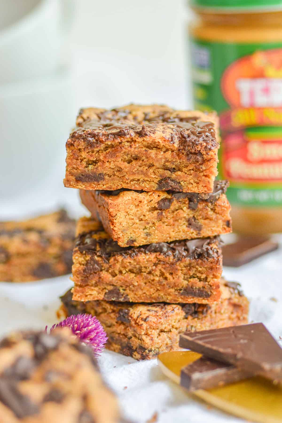 A stack for 4 vegan dairy free peanut butter chocolate chip blondies on a white cloth.