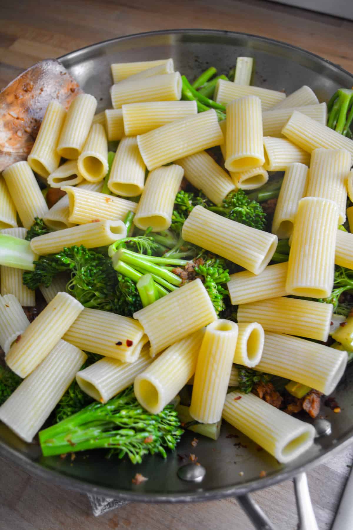 Pasta added into the pan with the broccolini and vegan sausage.