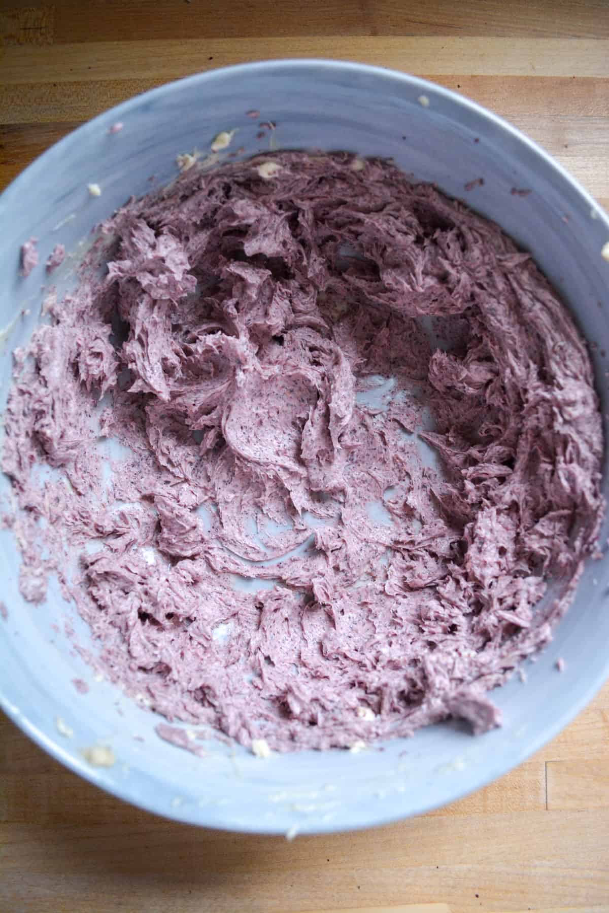 Blueberries mixed into the butter in a large mixing bowl.