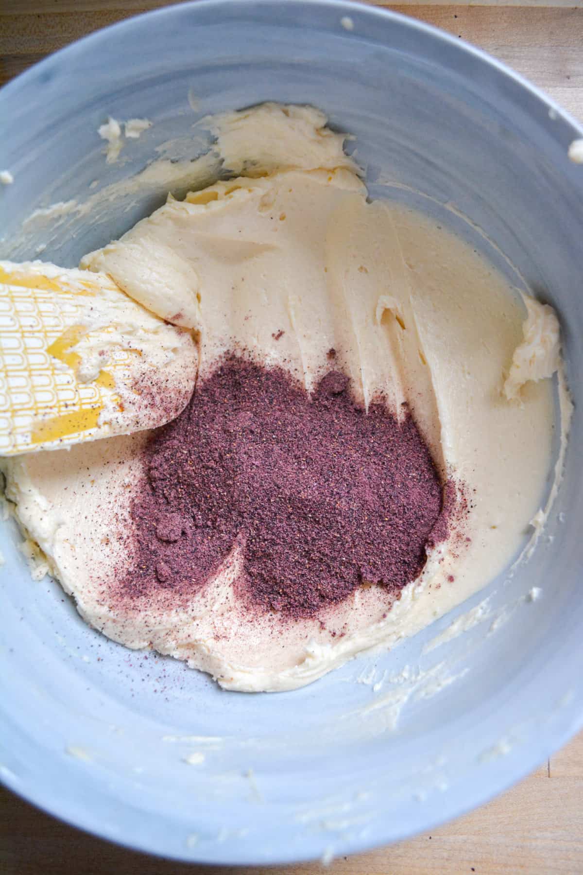 Creamed butter in a bowl with blueberry powder.