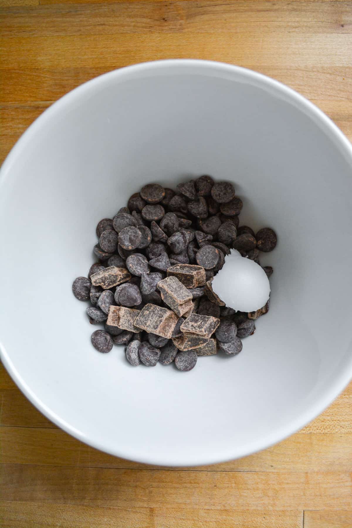 Chocolate chips and coconut oil in a small white bowl.
