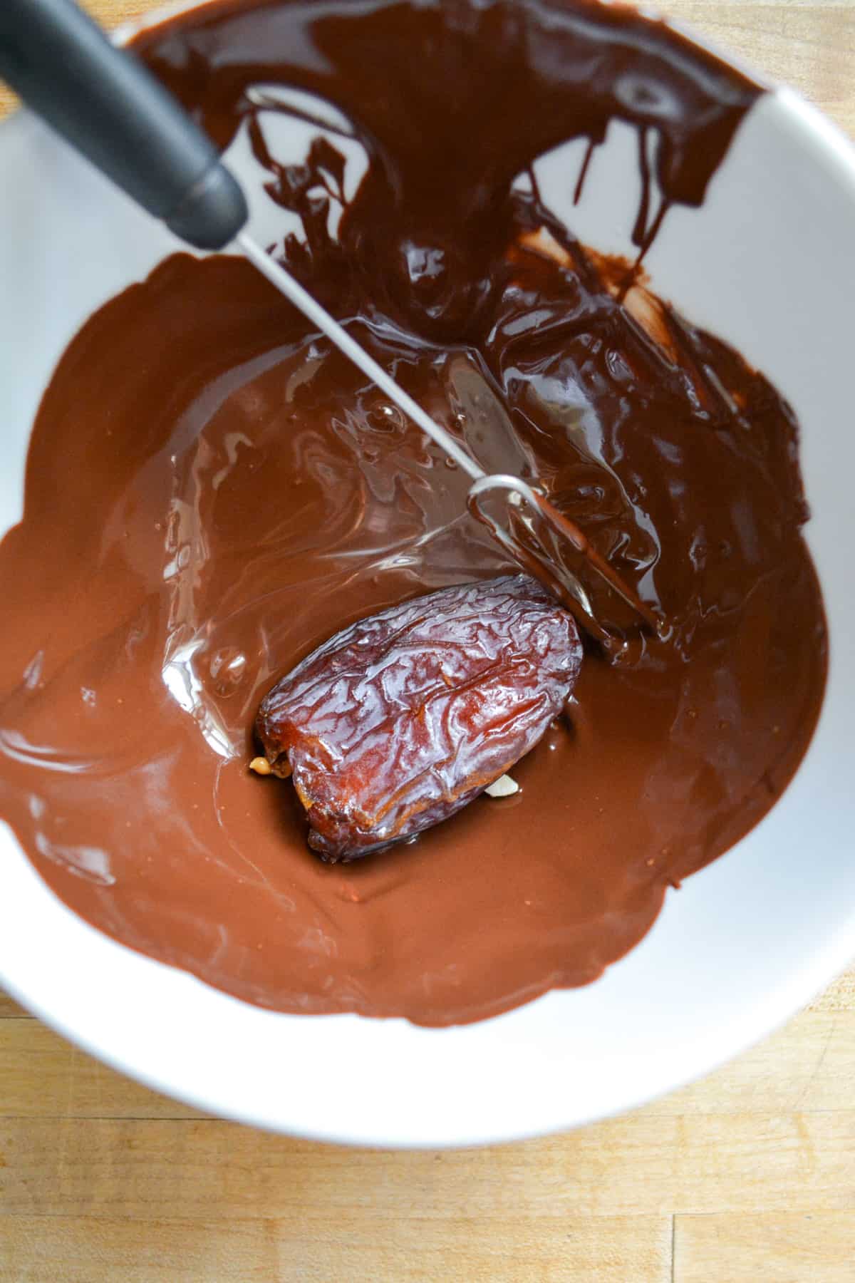 Date being covered in the melted chocolate. 