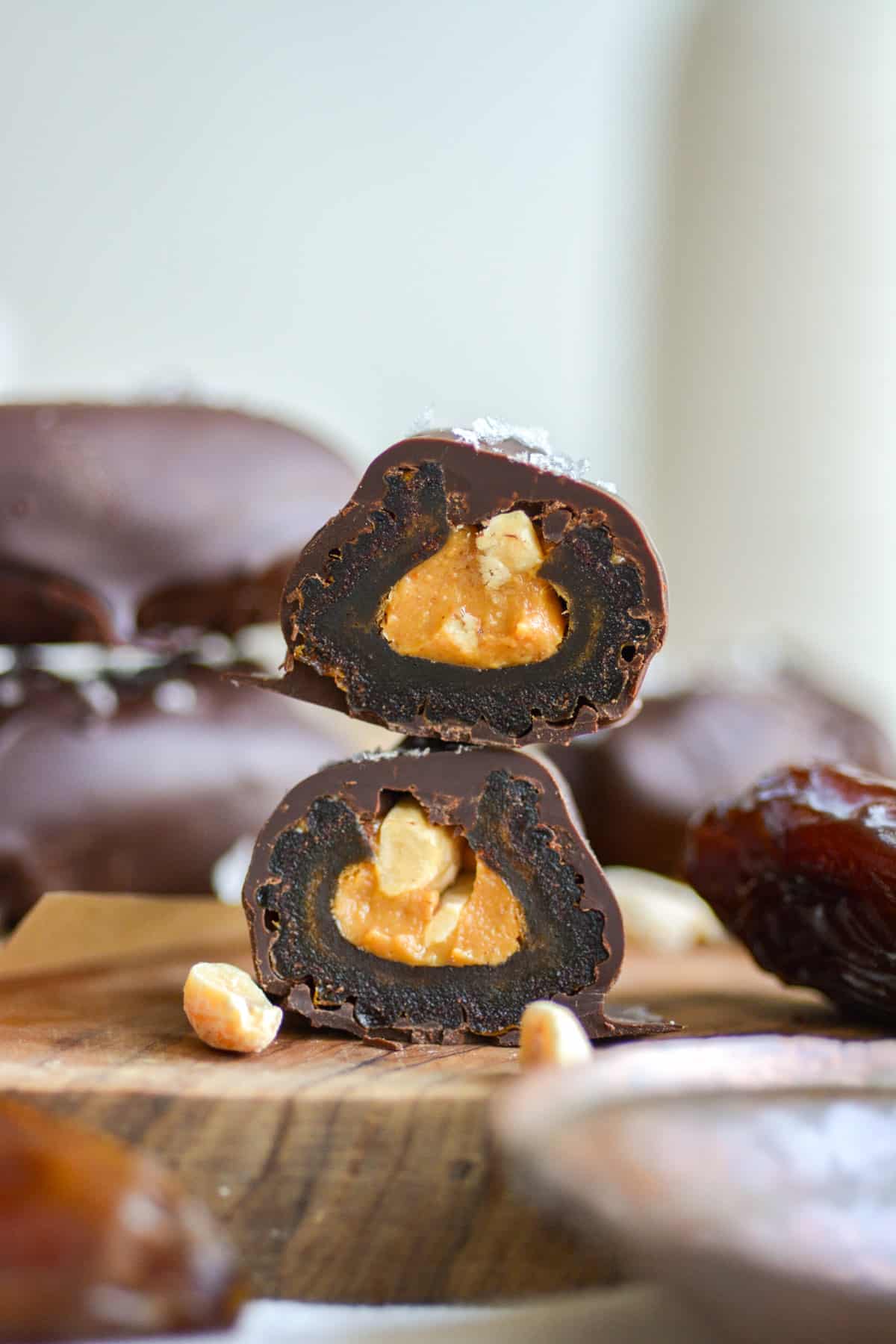 A chocolate covered date stuffed with peanut butter cut in half and stacked on top of each other on a wooden board.