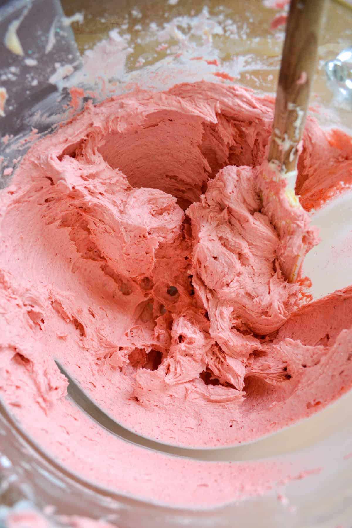 Strawberry frosting in a glass mixing bowl.