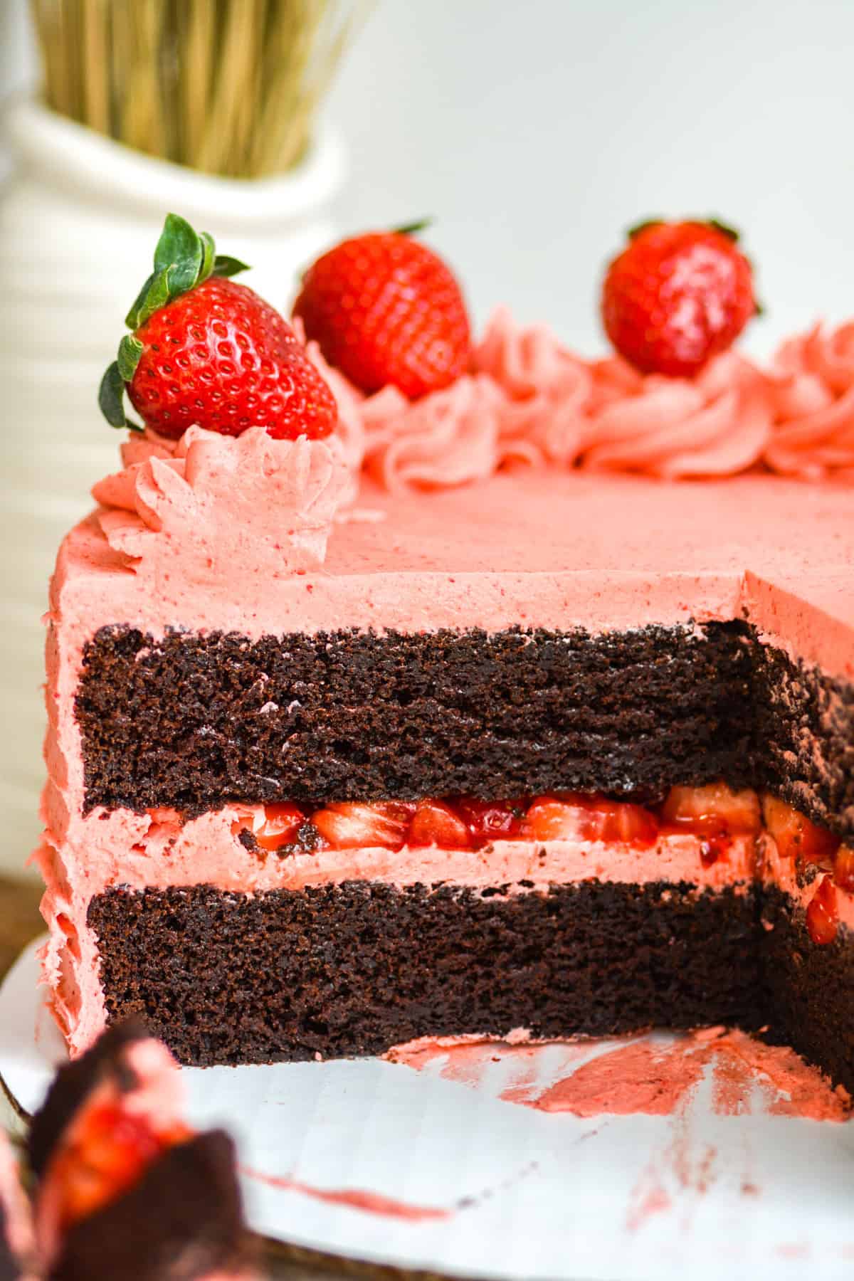 Chocolate Strawberry Cake on a cake board with a slice taken out of it.