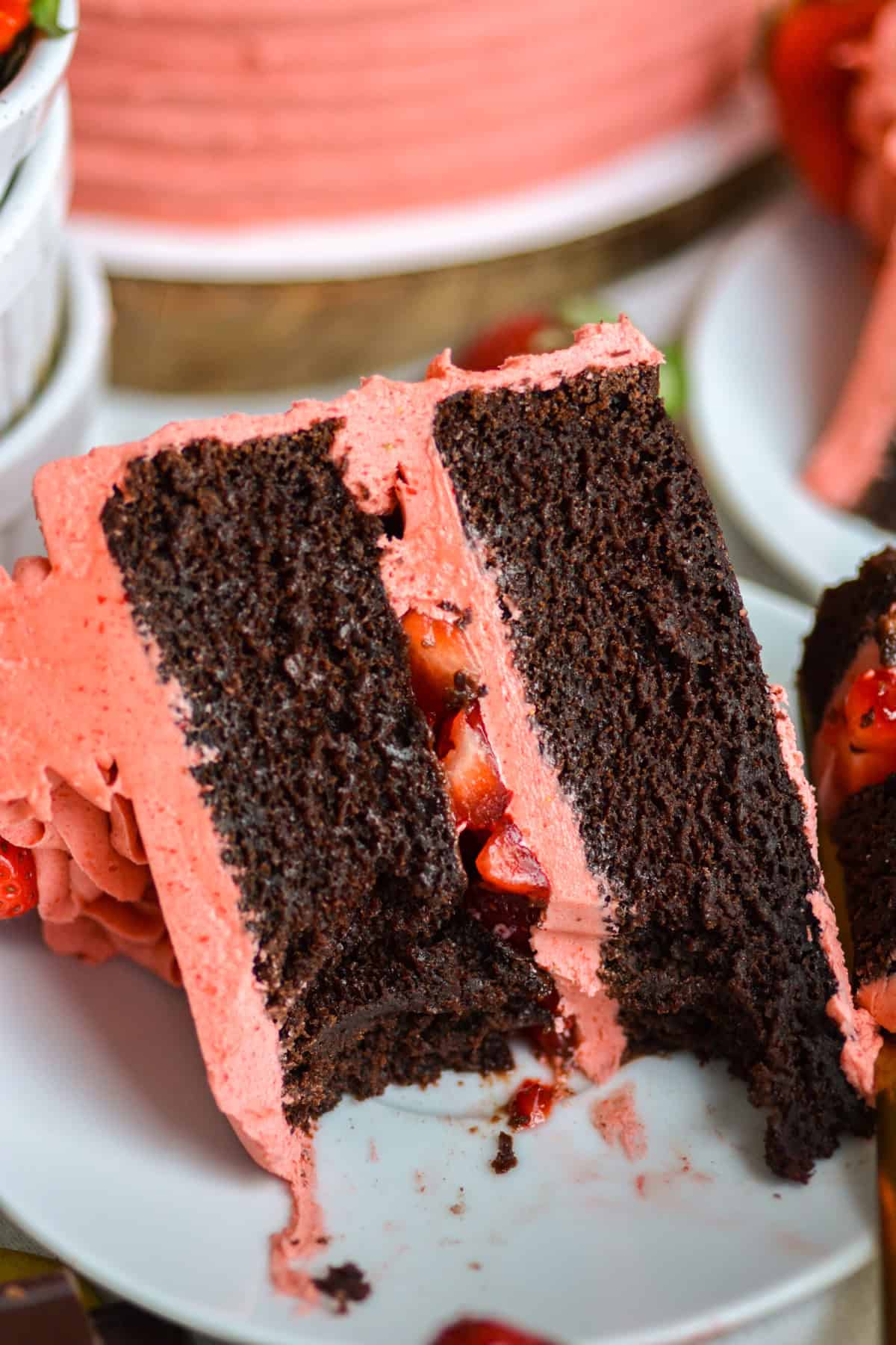 A bite taken out of a slice of Vegan Chocolate Strawberry Cake on a small plate.