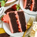 A slice of Chocolate Cake with Strawberry Frosting on a white plate.