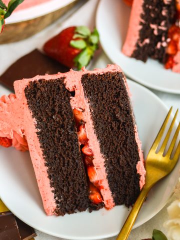 A slice of Chocolate Cake with Strawberry Frosting on a white plate.