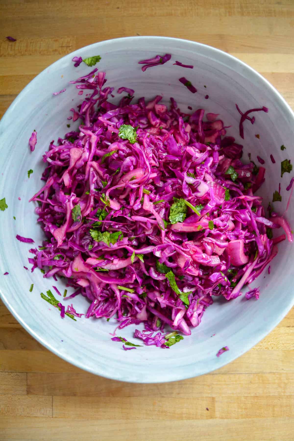 Finished red cabbage slaw in a marble bowl ready to top tacos.
