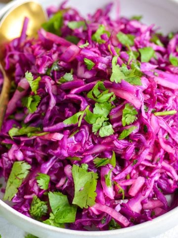 Cilantro Lime Red Cabbage Slaw in a white bowl with a gold spoon.
