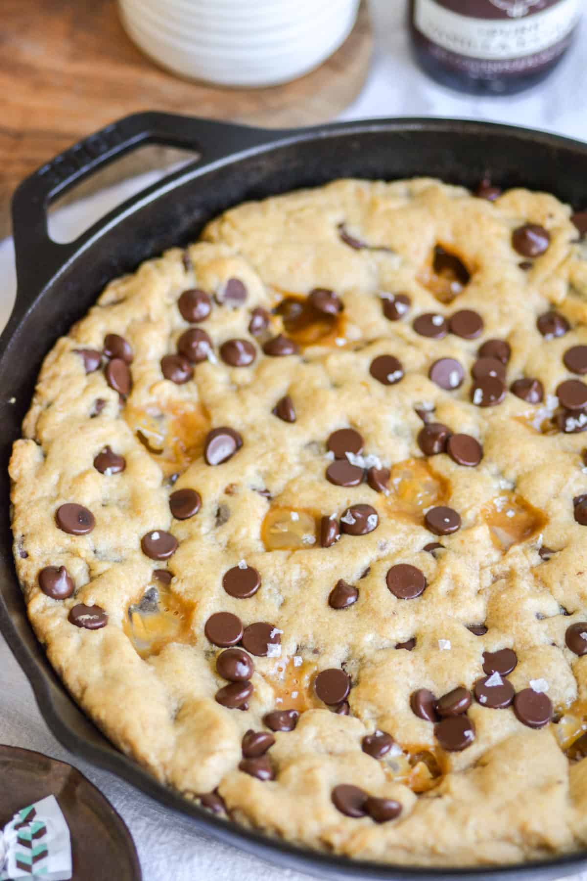 Baked Vegan Caramel Chocolate Chip Cookie Skillet in a black skillet  topped with sea salt.