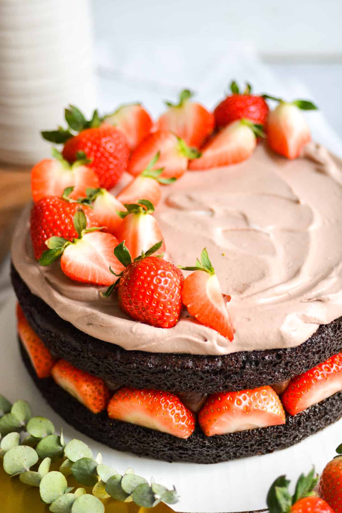 Vegan Chocolate Strawberry Fudge Cake topped with strawberries on a white cloth.