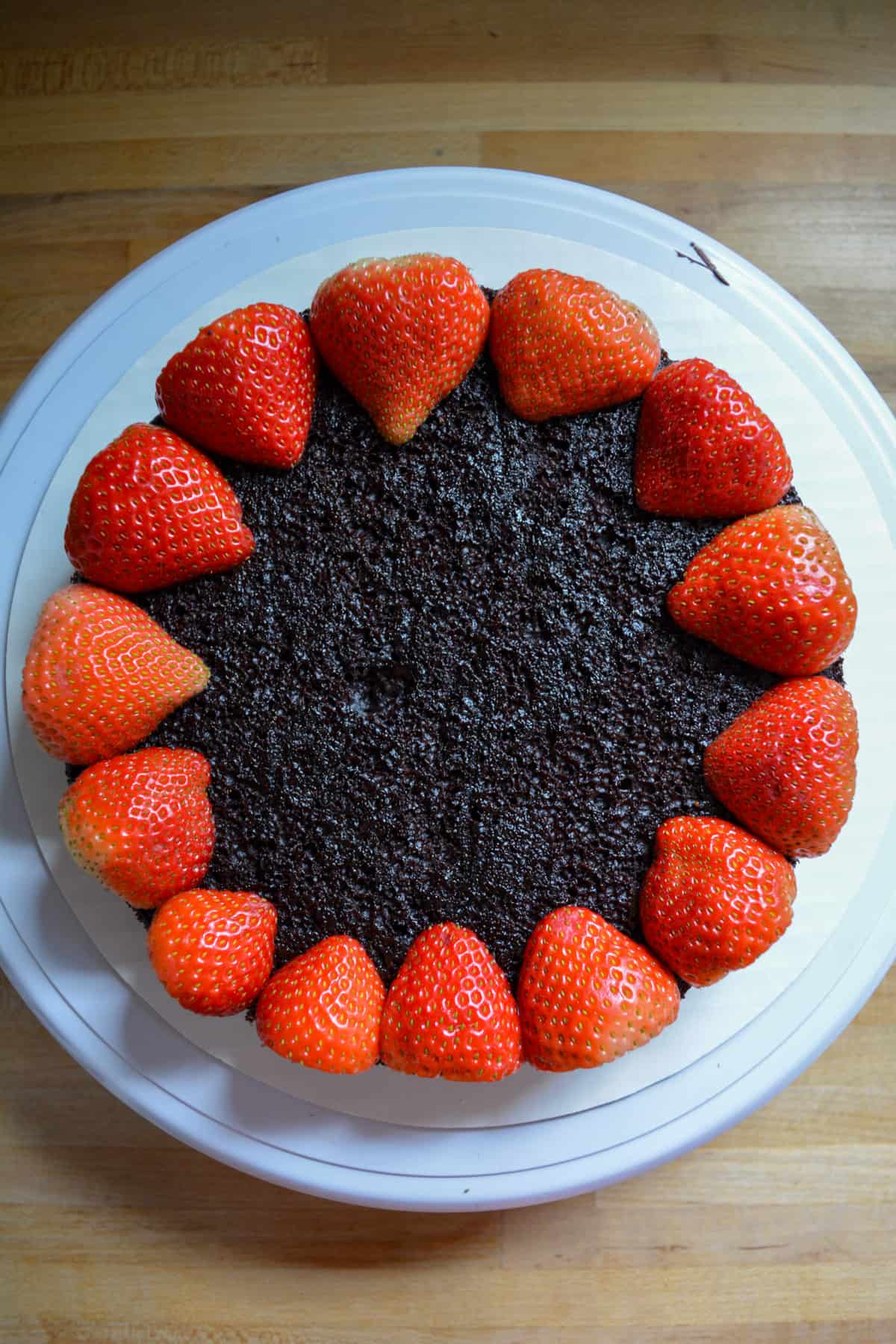 Vegan Chocolate cake layer with a halved strawberries around the perimeter.