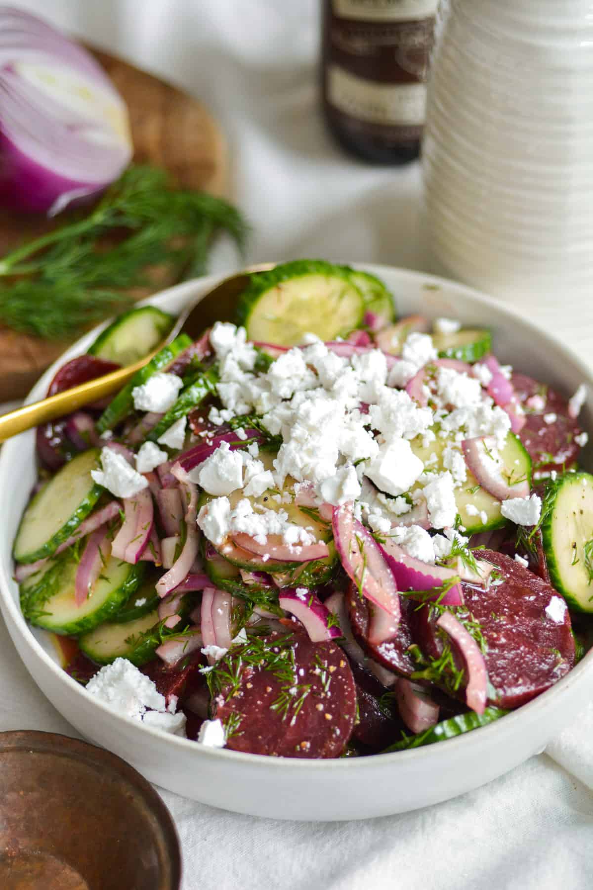 Beet Cucumber Salad in a white bowl topped with vegan feta.