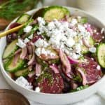 Beet cucumber salad in a bowl with a gold spoon.