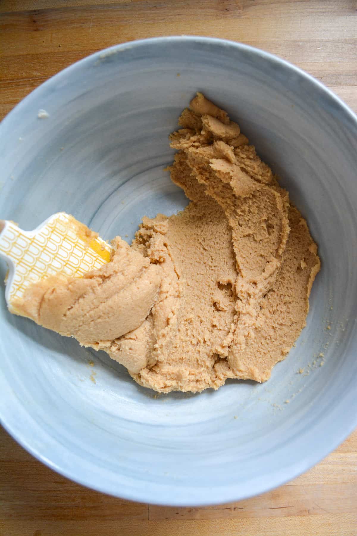 Vegan butter and brown sugar creamed together in a bowl with a spatula.