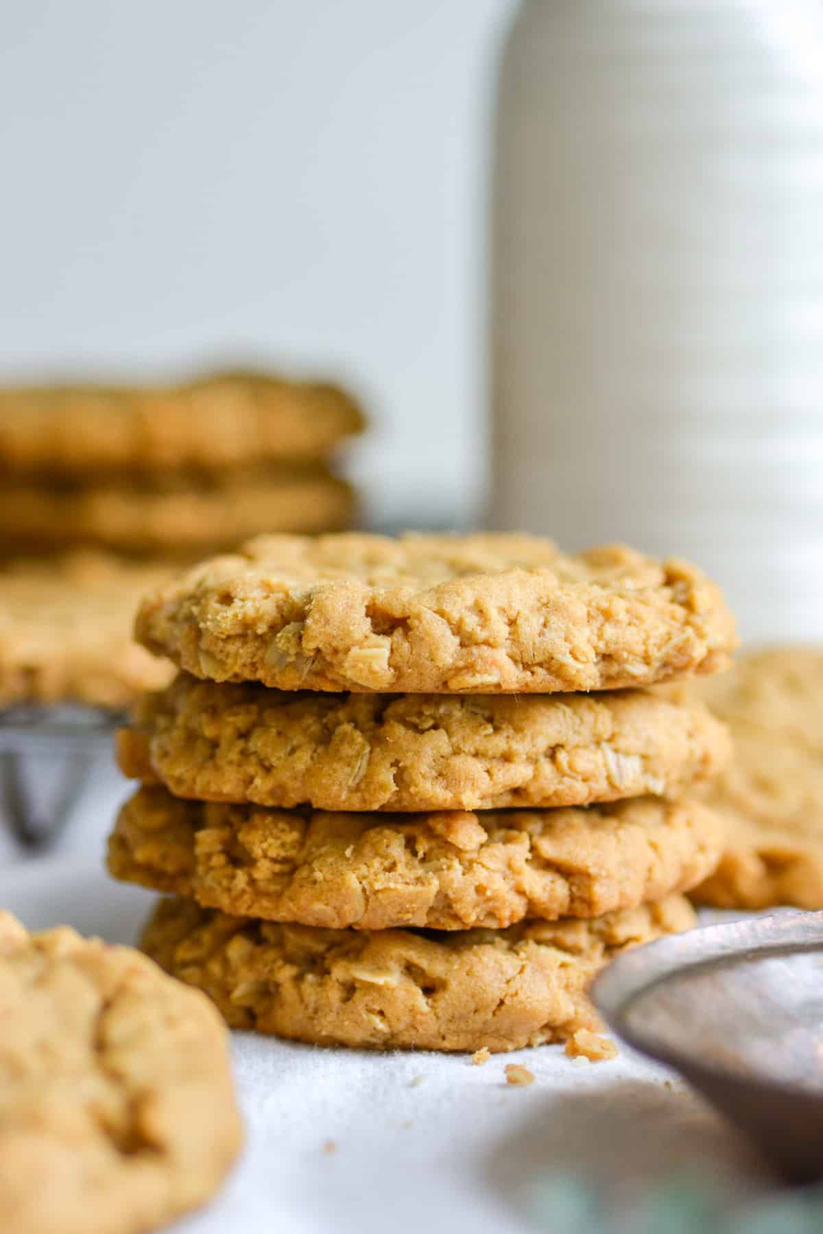 4 Vegan Oatmeal Peanut Butter Cookies stacked on top of each other on a white cloth.