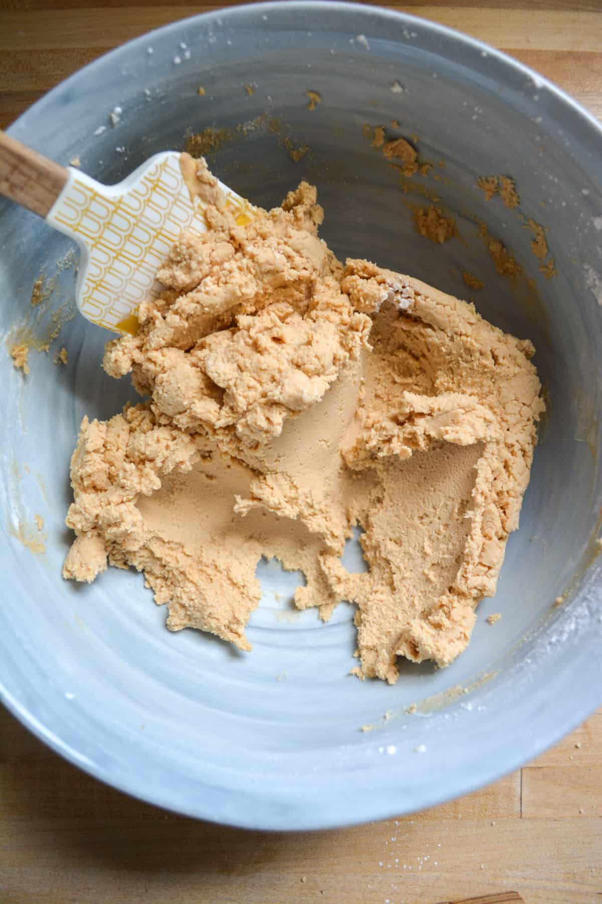 Powdered sugar mixed into the butter and cookie butter mixture with a spatula in the bowl.