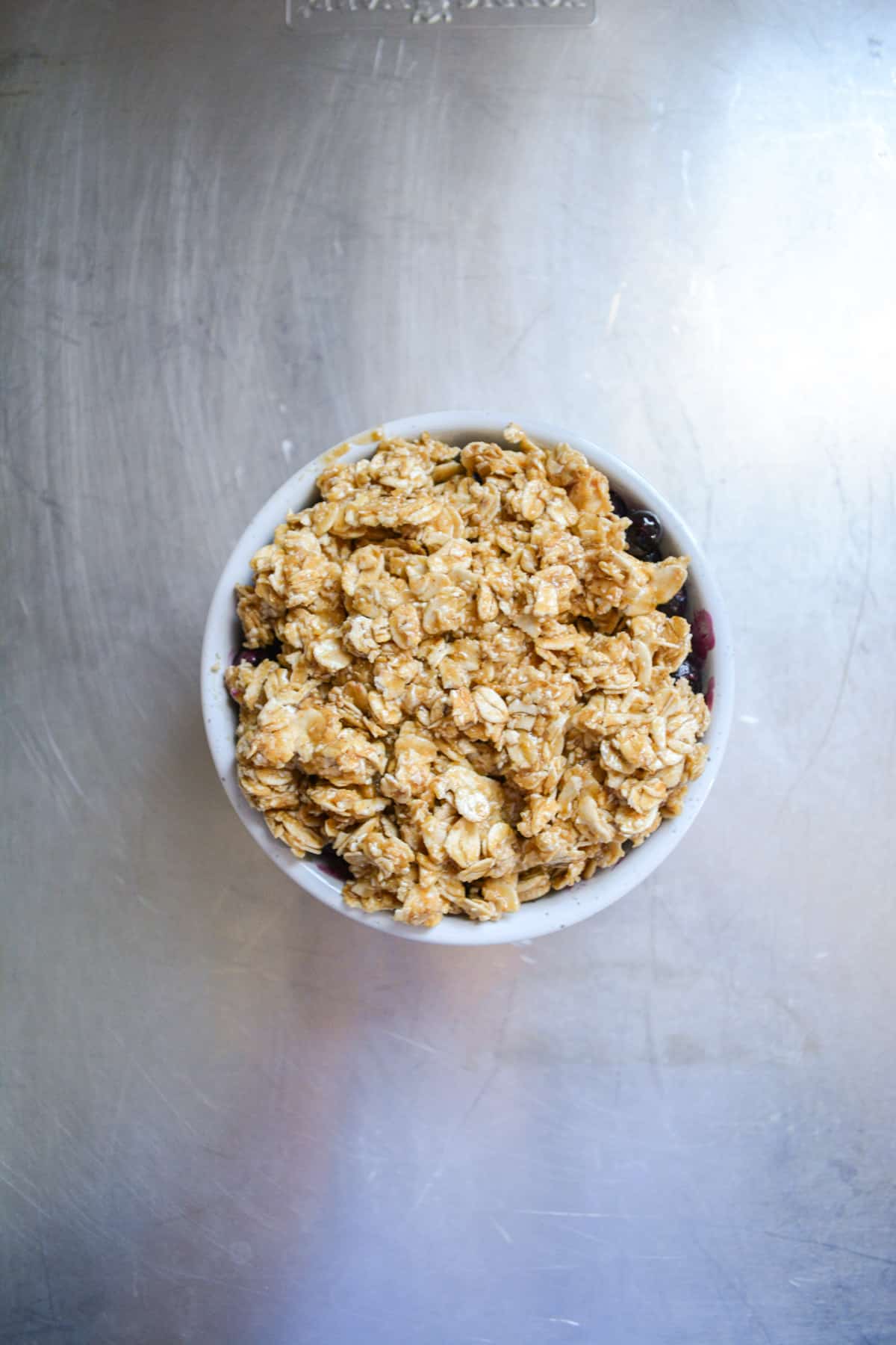 Singe Serving blueberry crisp topped with oat crumple and placed into a baking sheet.