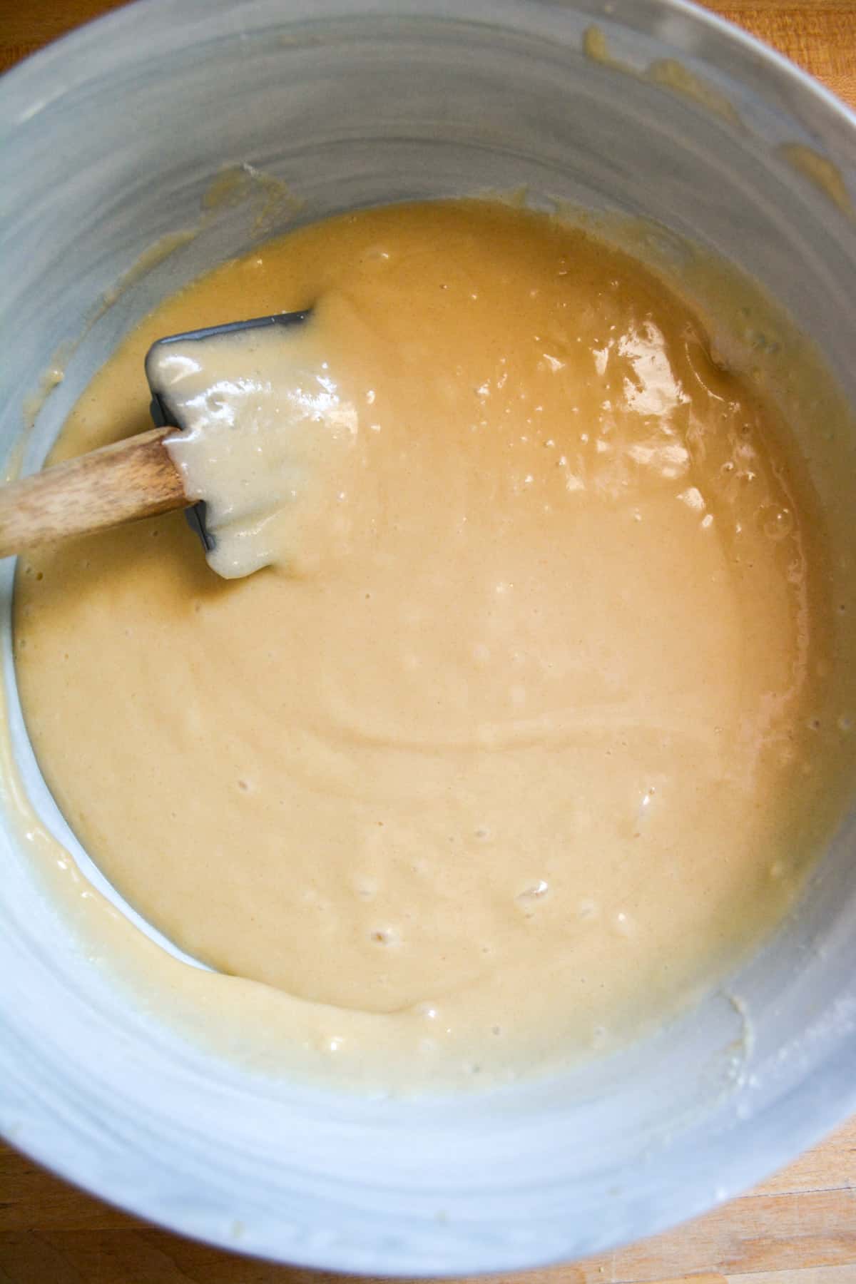 Cupcake batter in a mixing bowl with a rubber spatula off to the left.