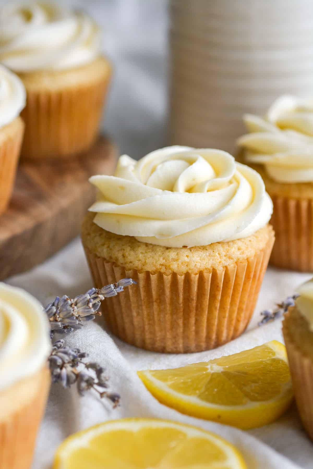 Vegan Lavender Cupcake topped with lemon frosting on a cloth with lemon slices in the foreground.