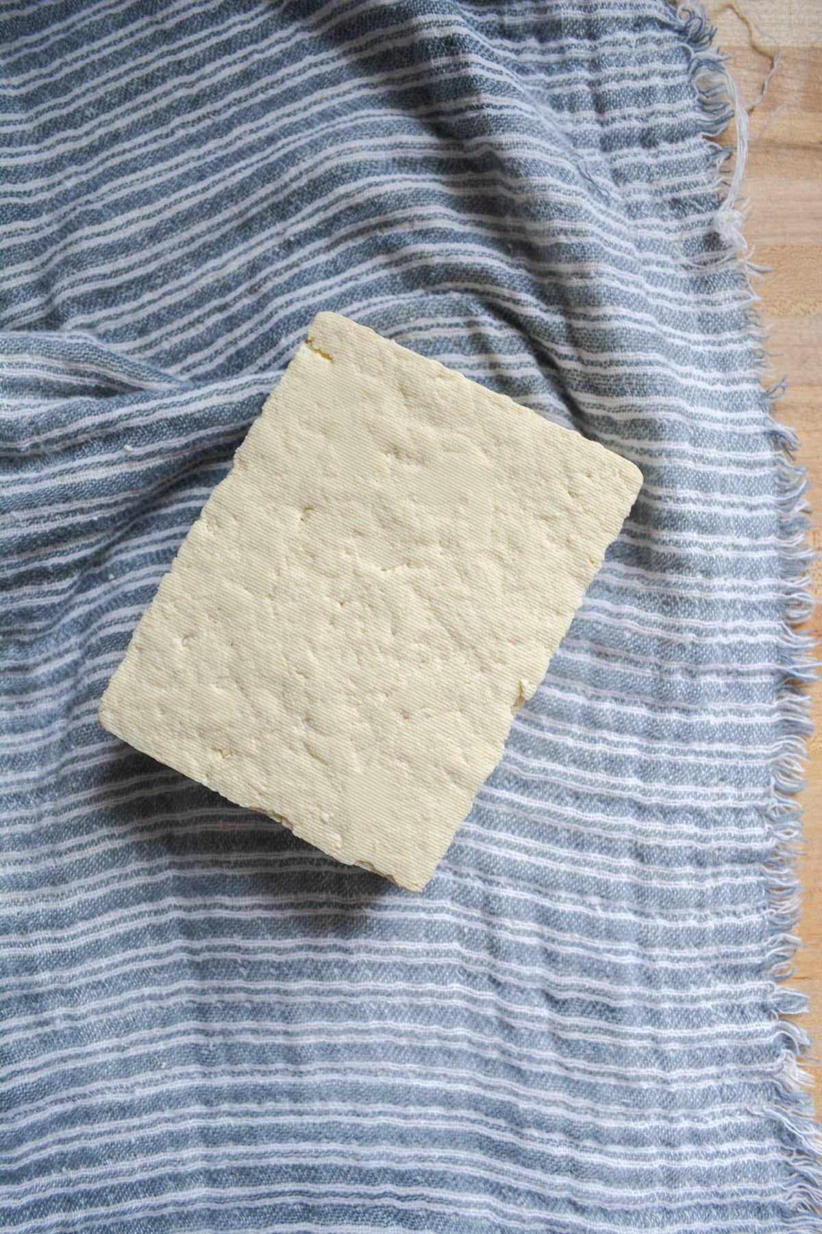 Block of tofu on a kitchen towel.