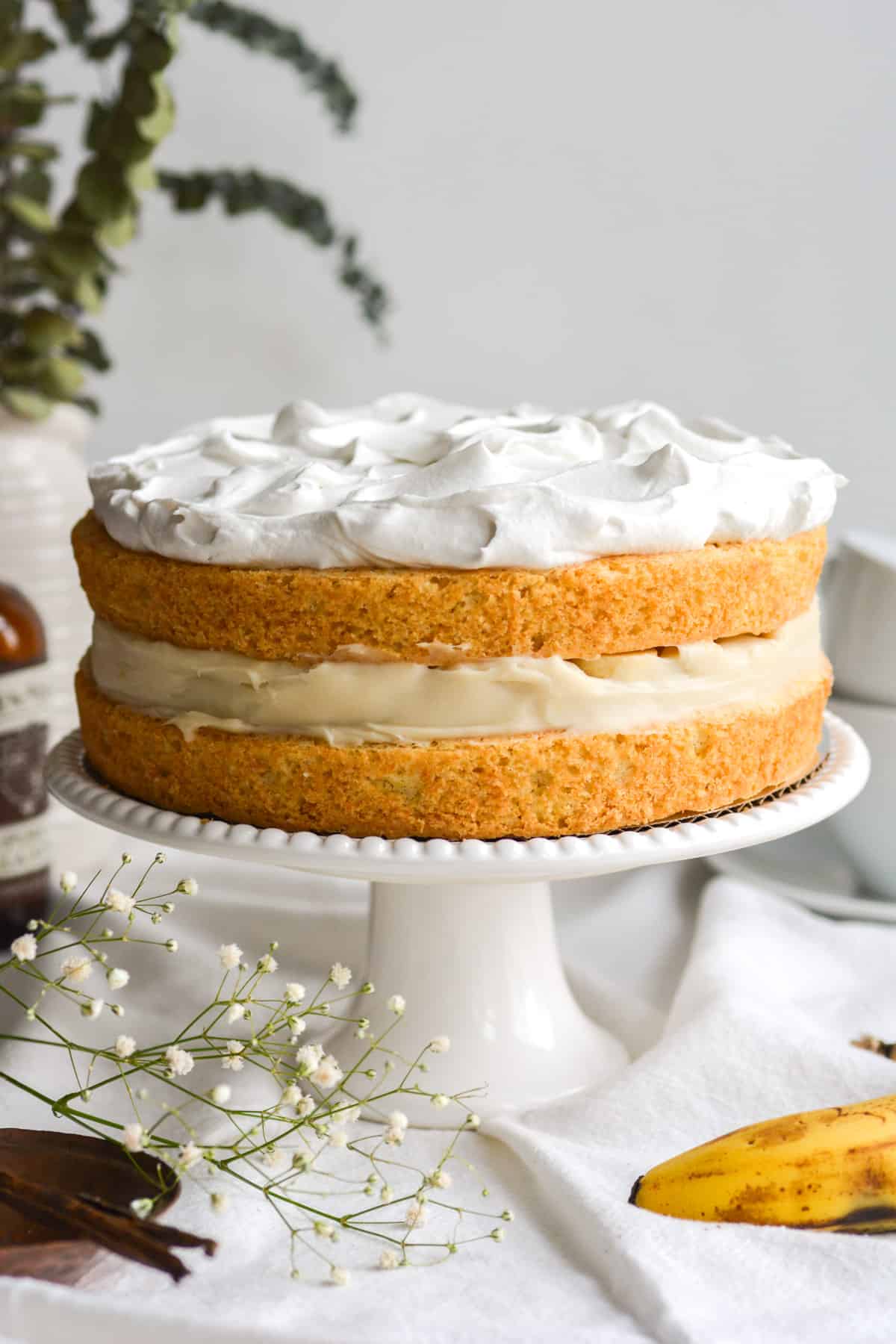 Vegan Banana Cream Pie Cake on a white cake stand.