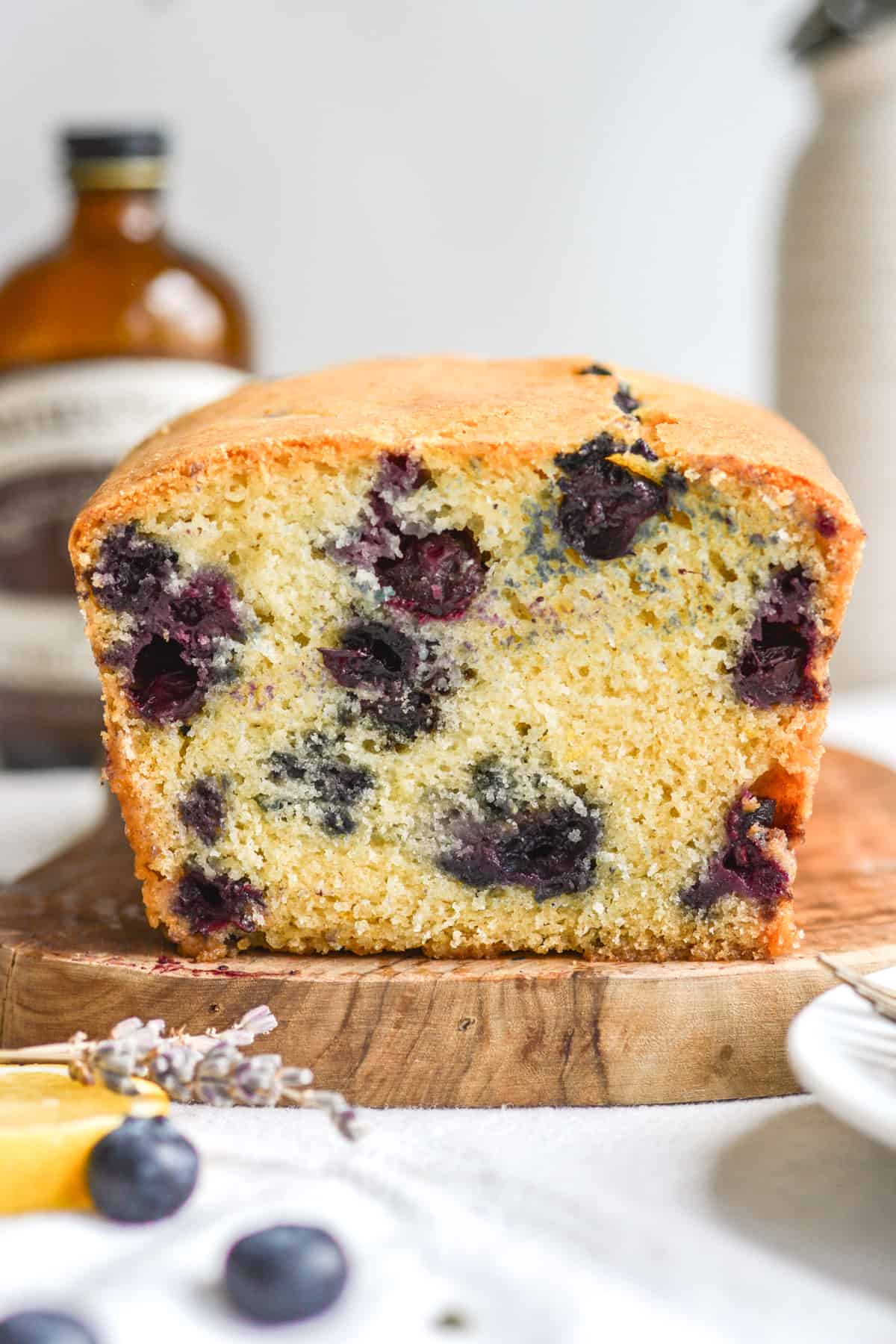 Cross section of the vegan blueberry lemon loaf cake on a small wooden board.