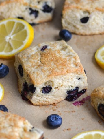 Vegan Blueberry scones on a baking sheet with lemon slices and blueberries scattered around.