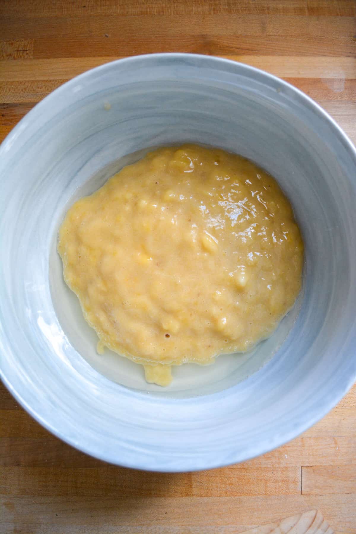 Mashed banana, oil and sugar in a mixing bowl.