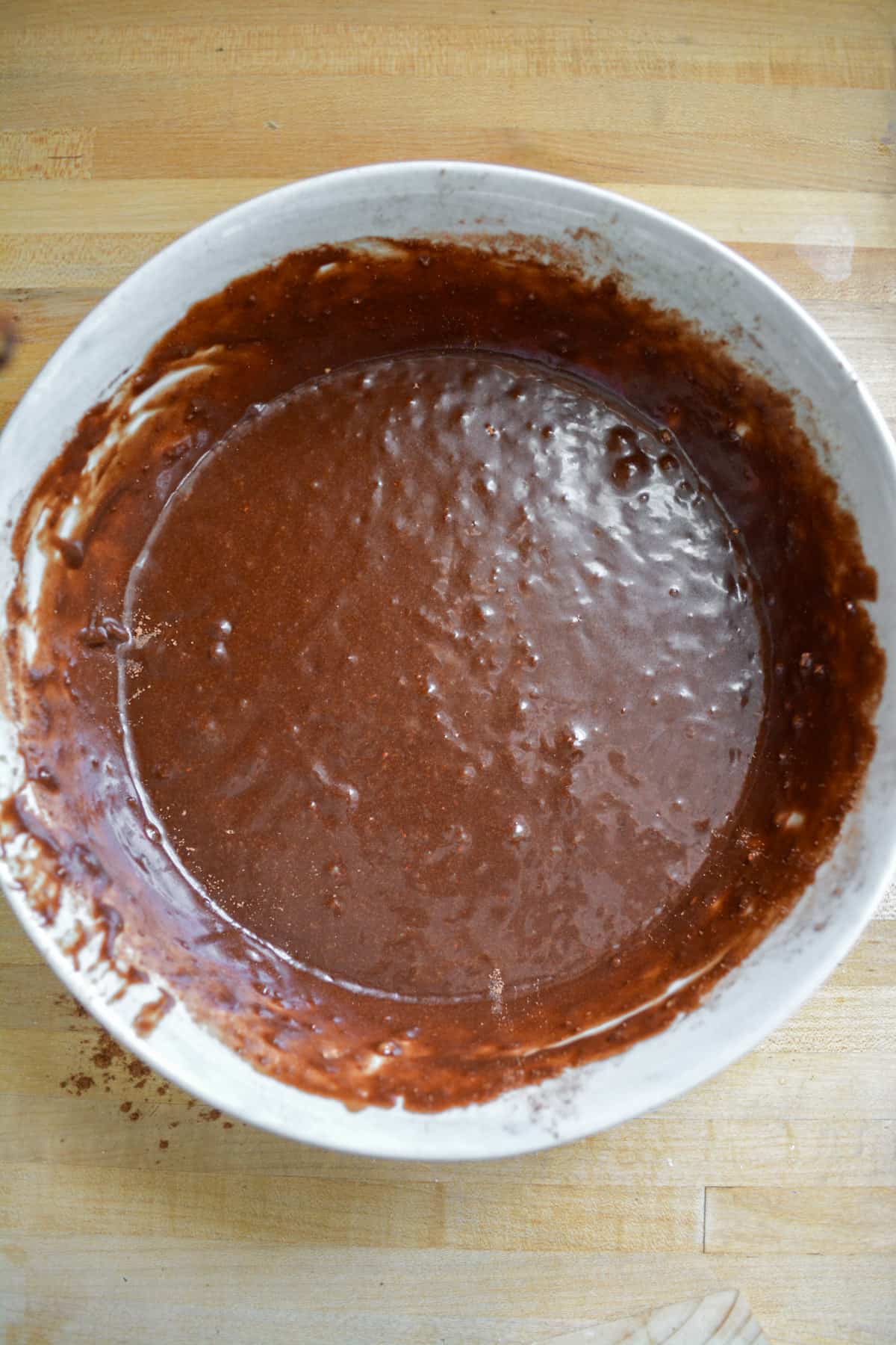 Cocoa powder whisked into the wet ingredients in a mixing bowl.