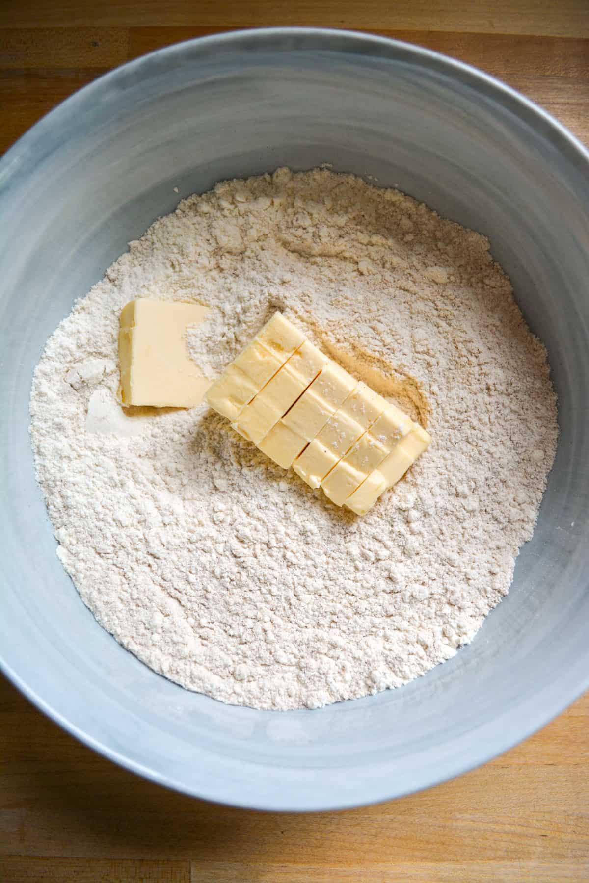 Cubed vegan butter added into the dry ingredients in the mixing bowl.