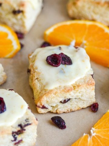 Vegan Cranberry Orange Scones on a baking sheet with orange slices.