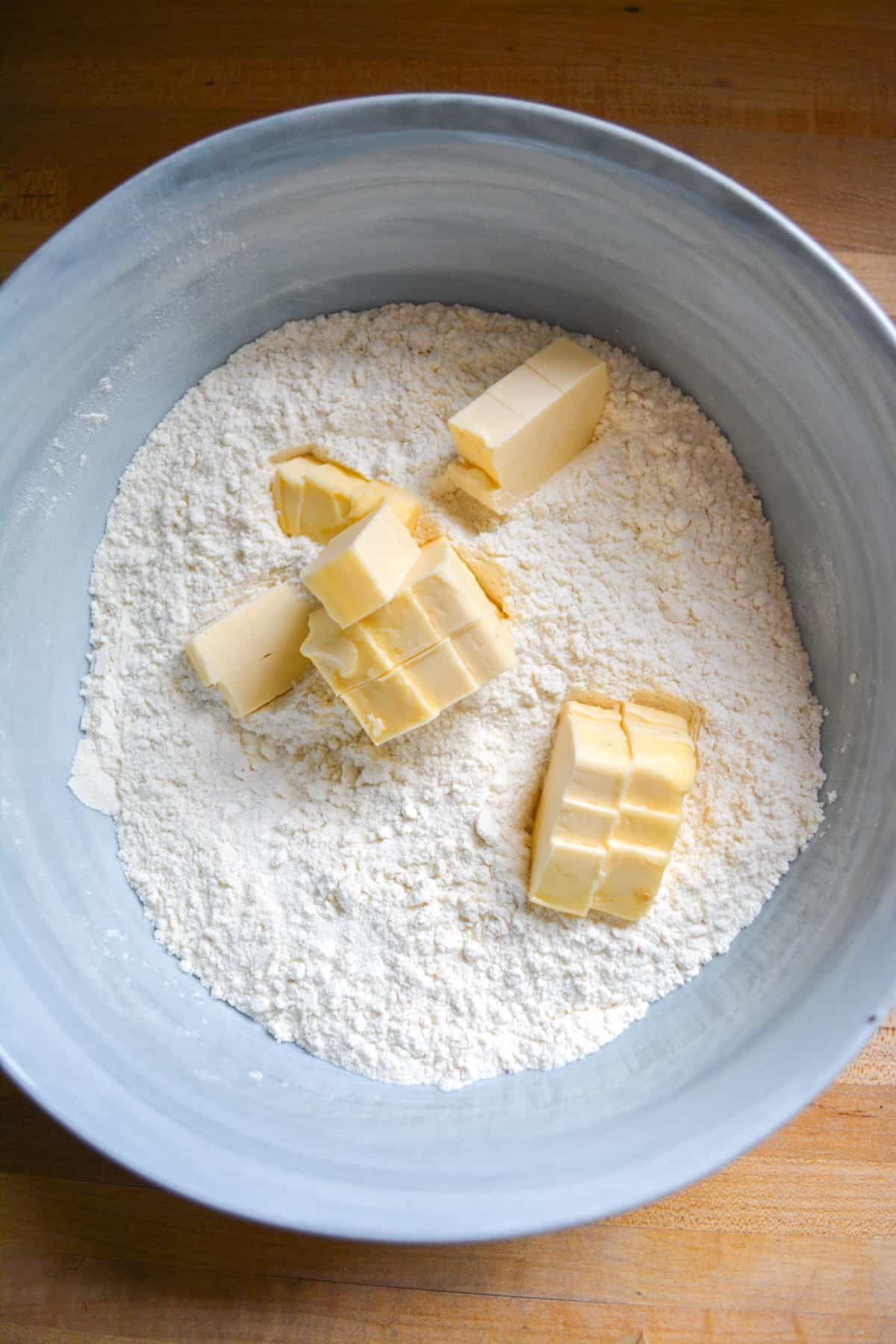 Dry ingredients mixed together in a mixing bowl with cold cubed butter adde on top.