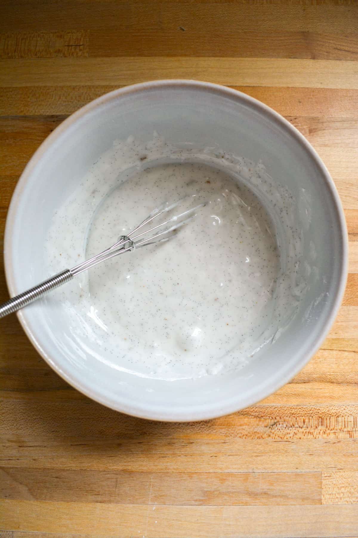 Vanilla bean glaze mixed together in a small bowl with a small whisk.