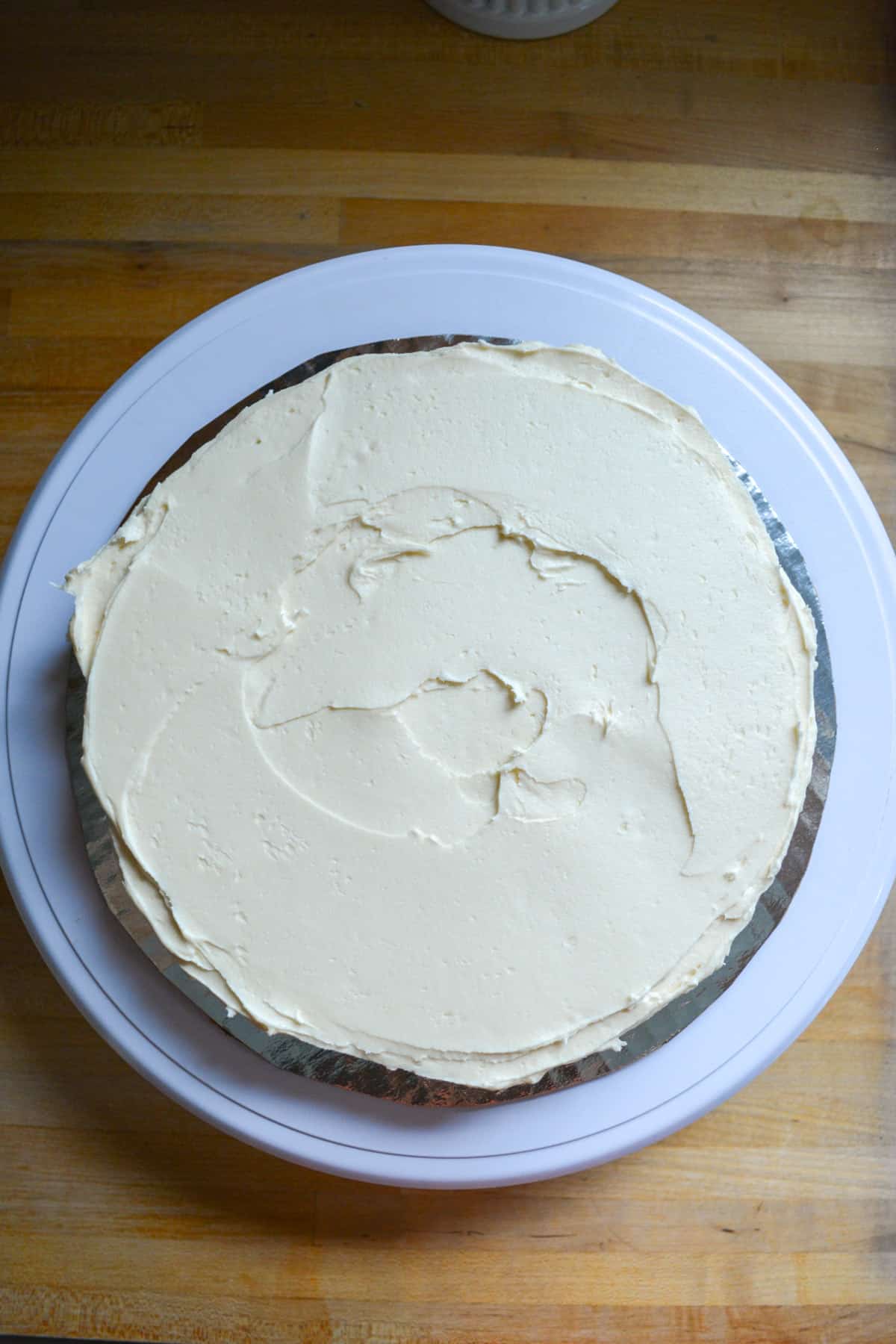 Frosting spread out across the cake layer on a cake board.