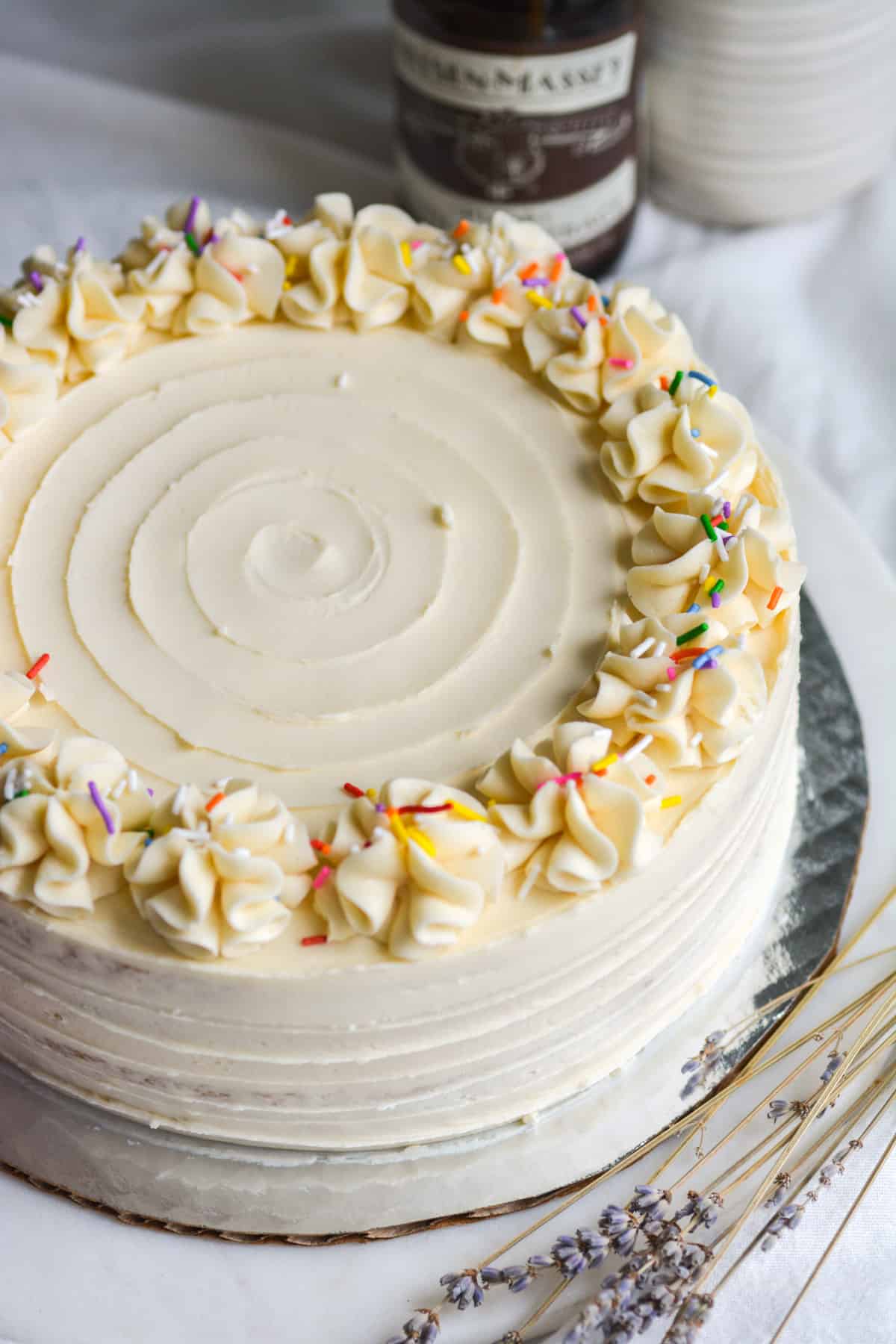 Frosted Vegan Vanilla Layer Cake on with a few sprinkles on top.