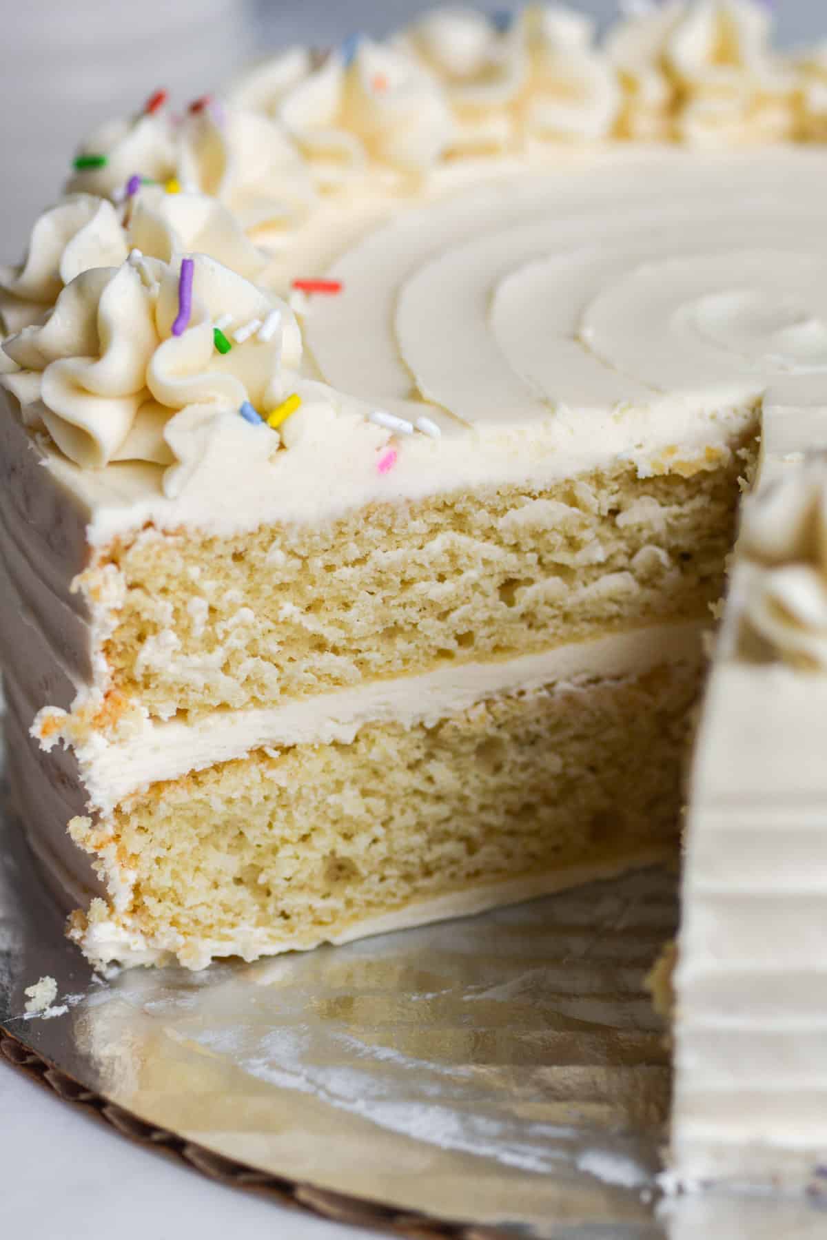 Vegan Vanilla Layer Cake with a slice taken out of it to show the texture of the inside.