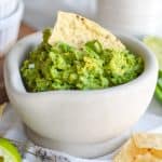 4 ingredient guacamole without cilantro in a small bowl with a tortilla chip sticking out of it.