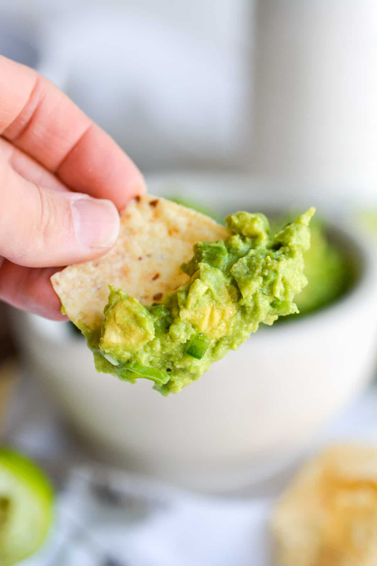 A tortilla chip with 4 ingredient guacamole without cilantro on it.