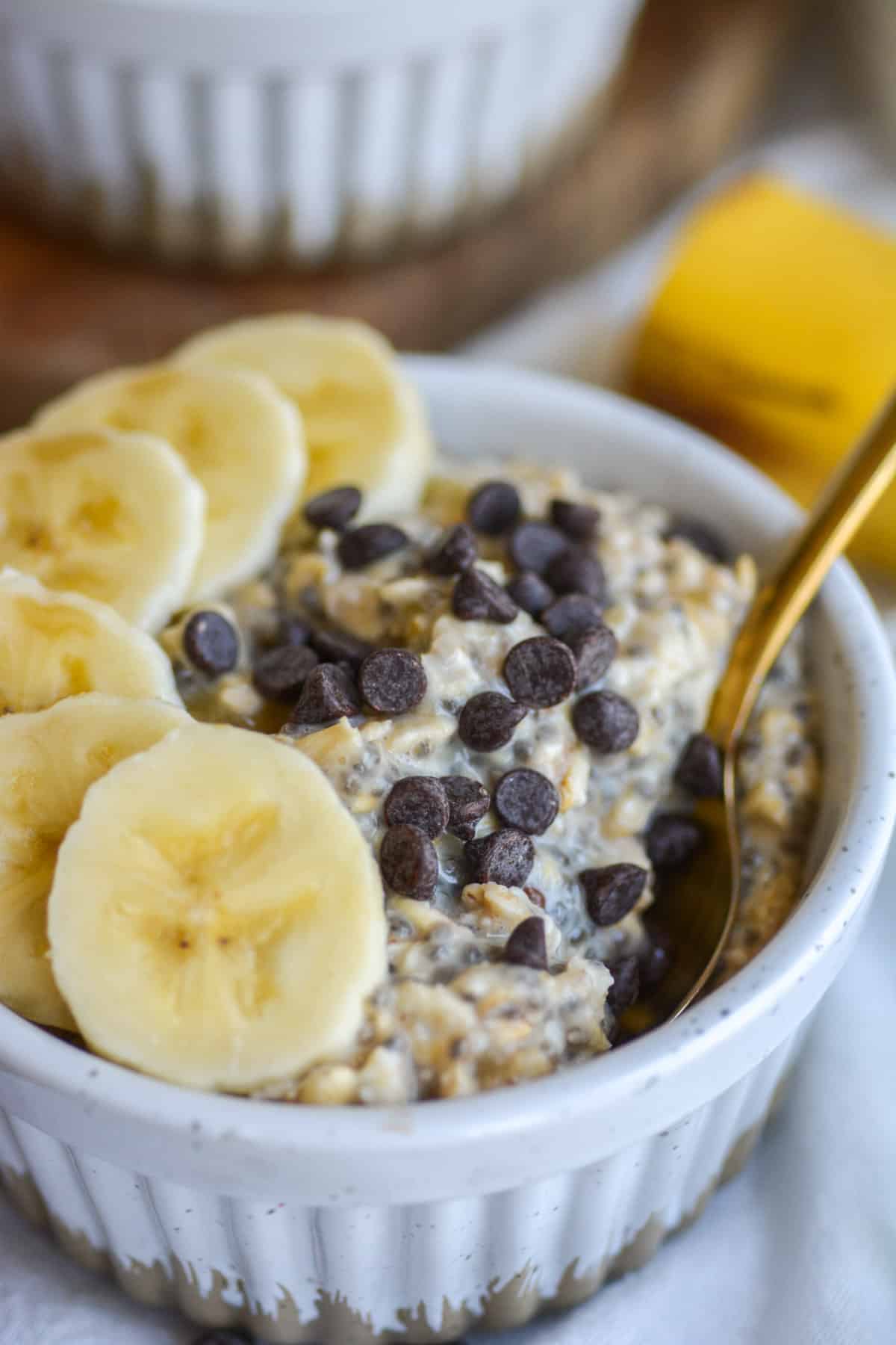 banana chocolate chip overnight oats in a ramekin with a spoon in it.