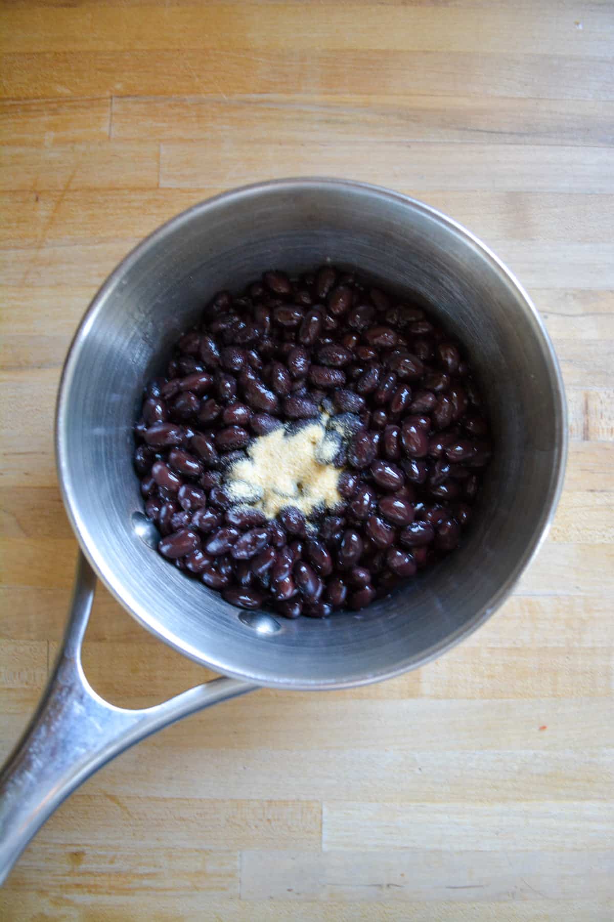 Black beans in a small saucepan with garlic and onion powder.