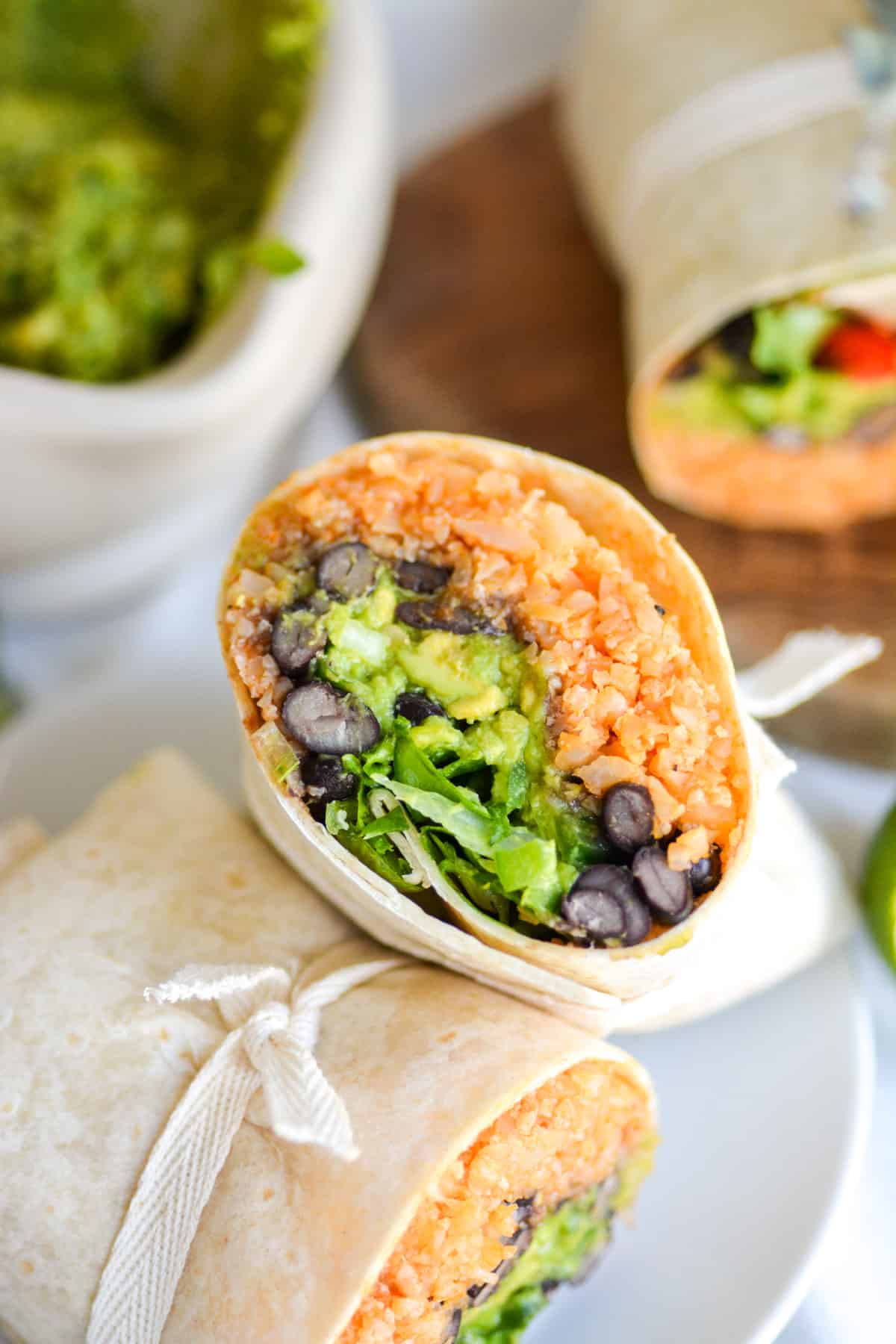 Vegan Black Bean Burrito cut in half to show the inside, leaning on the other half on a small plate.
