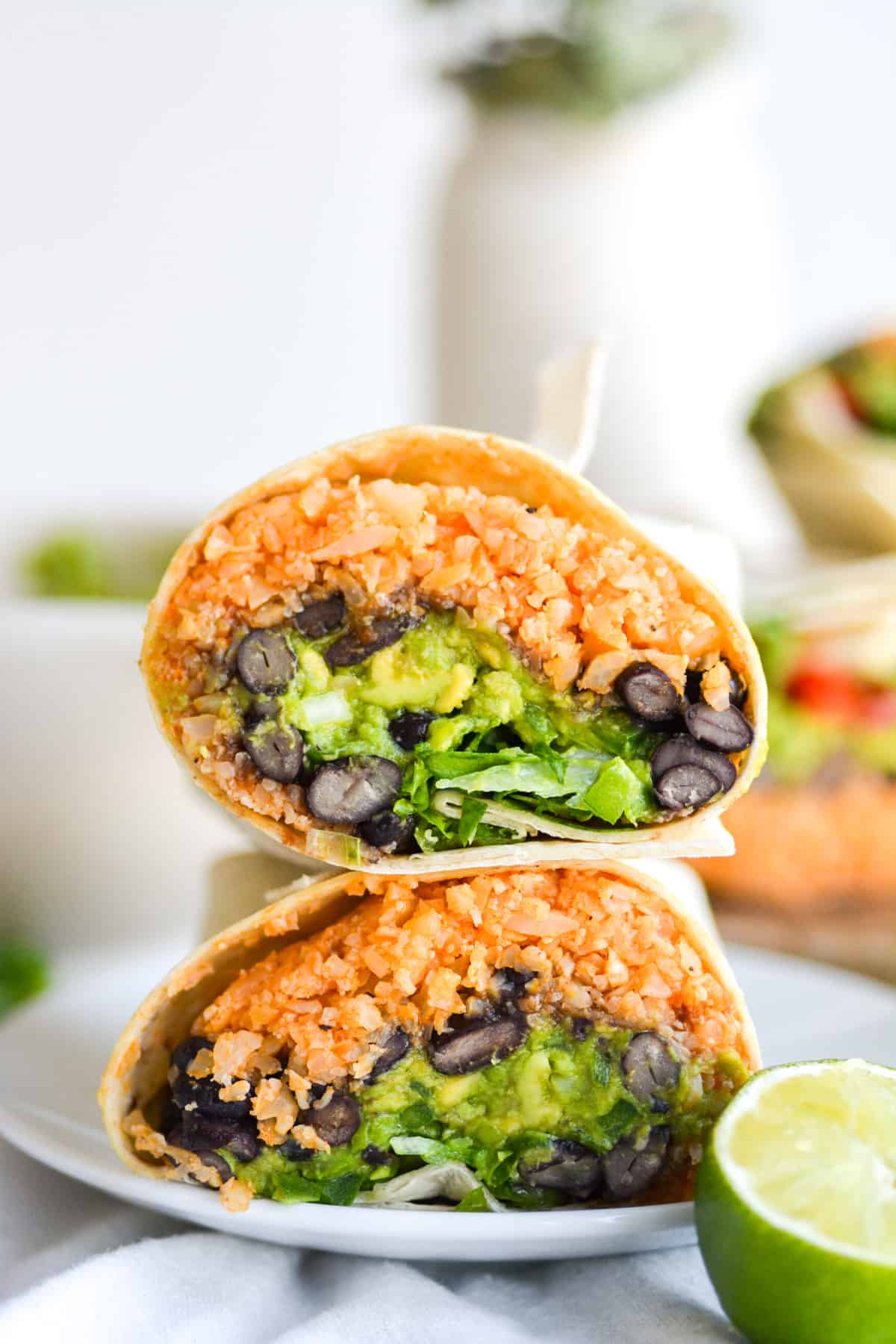 Black Bean Burrito cut in half. The halves are stacked on top of each other on a small plate.