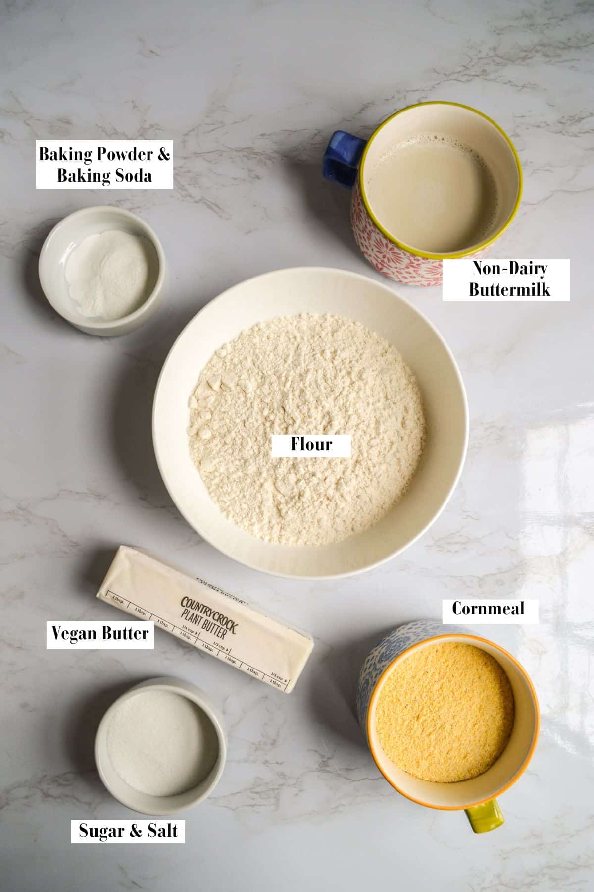 Ingredients for making vegan cornmeal drop biscuits on a marble surface.